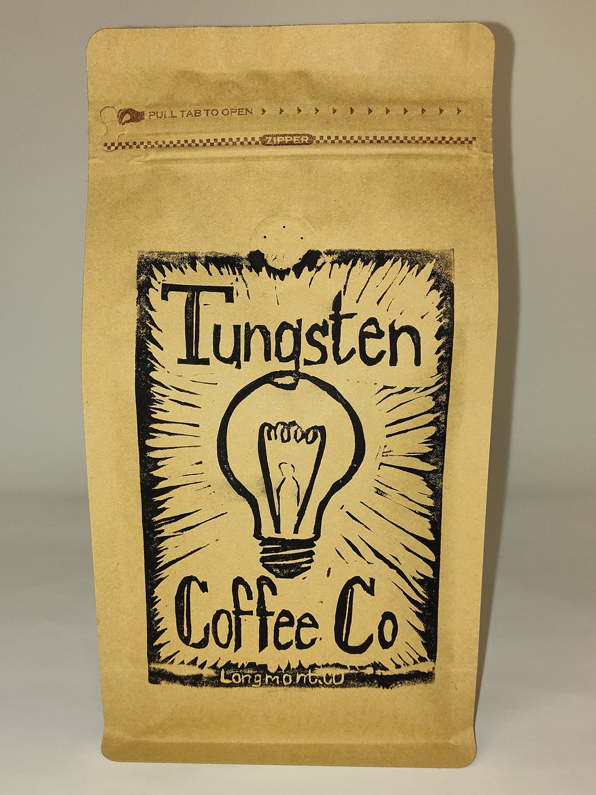 A kraft paper coffee bag with a black printed logo reading 'Tungsten Coffee Co' and a lightbulb illustration, standing upright against a plain light gray background.