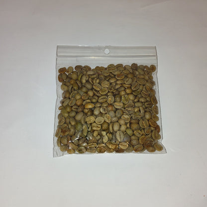 A small clear plastic zip-top bag filled with green coffee beans, photographed on a plain off-white background.
